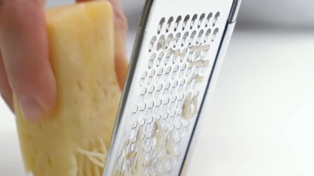 hand grating yellow cheese with a metal grater closeup