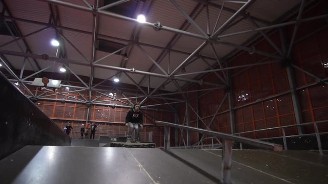 A male athlete performs a rollerblading trick in an extreme park and rejoices with a friend, slow motion