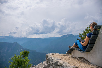 The girl photographer is resting on the top of the mountain sitting on an unusual bench.