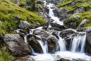 The waterfall of a mountain river with rocks in the Carpathians.