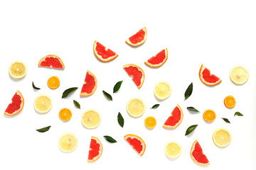 Pattern of fresh fruits on a white background, top view, flat lay.   Composition of green leaves and slices of citrus fruits: grapefruit, lemon, mandarin. Healthy food background, wallpaper, collage.