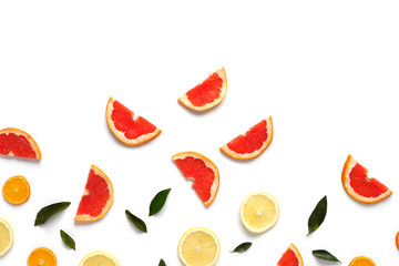 Pattern of fresh fruits on a white background, top view, flat lay.   Composition of green leaves and slices of citrus fruits: grapefruit, lemon, mandarin. Healthy food background, wallpaper, collage.