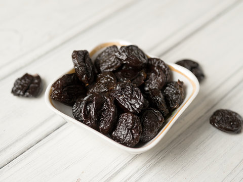Prunes in ceramic plate on wooden background