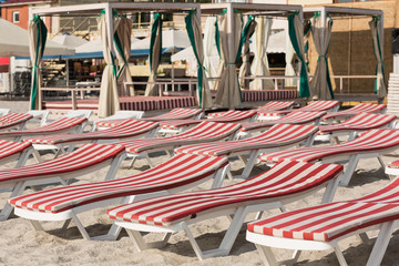 Fototapeta na wymiar chaise lounges with red mattresses stand on the sand on the beach, no people