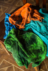 Pile of colorful dirty rags laying nearby chopper on the wooden chair. Old garage