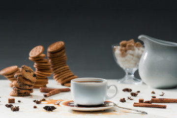 Cup with spilled coffee on table with biscuits and spices