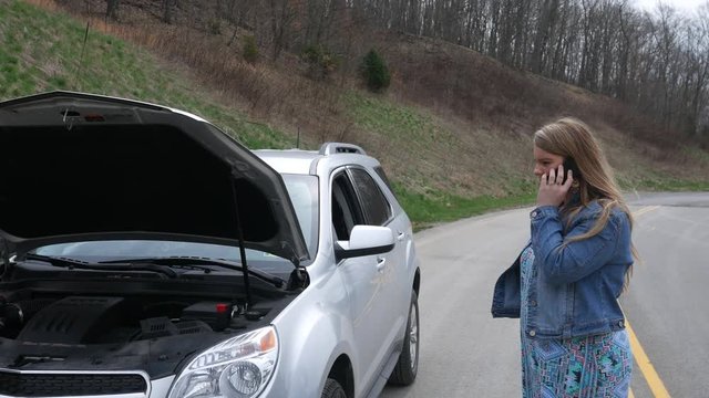 A woman calls for help on the side of the road near broken vehicle