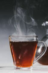 Steaming black tea in glass cup on table