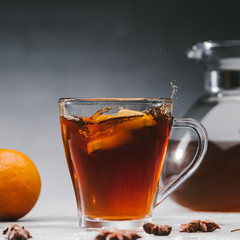 Citrus pieces splashing in cup with black spicy tea