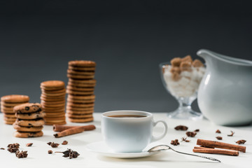 Cup of black coffee on table with cookies and spices