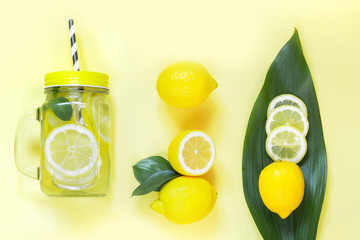 Summer lemon composition for cooking detox lemonade with mint and ice in mason jar on yellow. Tropical concept. Top view. Flat lay.