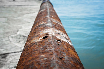 An old rusty pipe with holes close up.