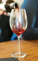 Pouring red wine from bottle into glass. Wine degustation.