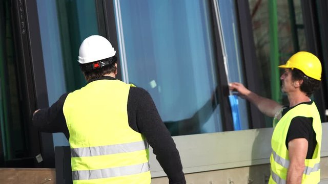 Construction workers checking glass windows before siting and installation