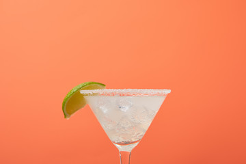 close up view of refreshing alcohol margarita cocktail with lime and ice isolated on orange