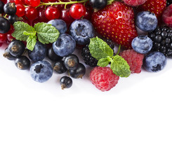 Mix berries and fruits at border of image with copy space for text. Ripe blueberries, blackberries, raspberries, currants and strawberries on white background. Top view. Black-blue and red food.