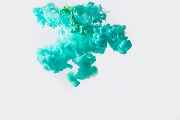 close up view of mixing of green and bright turquoise paints splashes in water isolated on gray