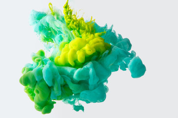 close up view of mixing of green, yellow and bright turquoise paints splashes in water isolated on...