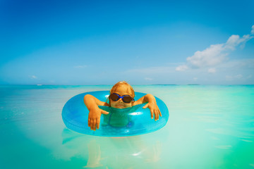 little girl with inflatable ring has fun on tropical beach