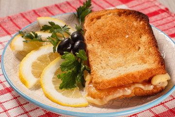 Good and delicious food and beverages for breakfast. Toast with butter and cheese, slices of lemon and olives on plate