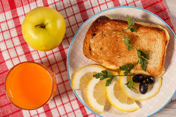 Good and delicious food and beverages for breakfast. Toast with butter and cheese, slices of lemon and olives on plate
