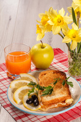 Good and delicious food and beverages for breakfast. Toast with butter and cheese, slices of lemon and olives on plate