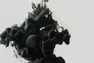 close up view of black paint splash in water isolated on gray