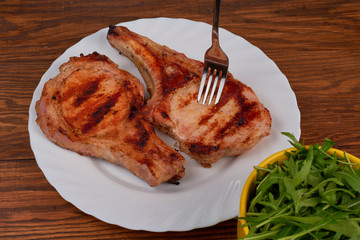 Pork grilled with fresh arugula leaves on a white plate. Top vie