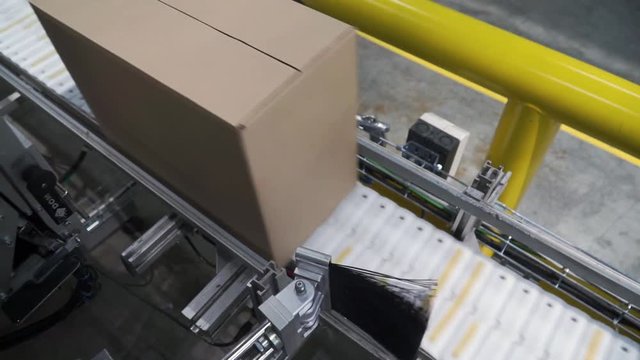 Cardboard boxes on conveyor belt in factory. Clip. Production line on which the boxes move