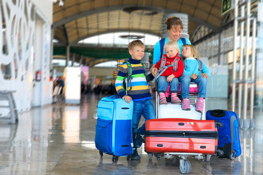 family travel -mother with kids and suitcases in airport