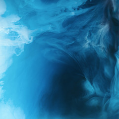 full frame image of mixing of blue, black and white paints splashes  in water