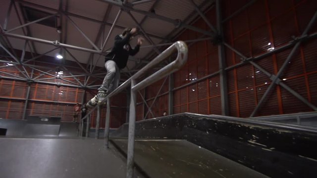 Slider shooting as a man on rollers performs grind in an extreme park, slow motion