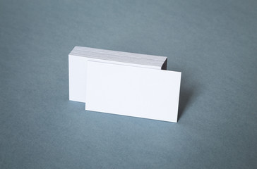 Blank white business cards with shifted front card on a grey background