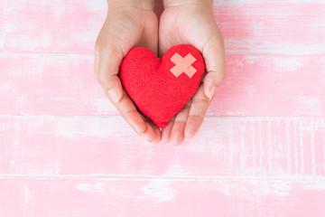 World health day, World MALARIA day, Healthcare and medical concept. Woman hand holding handmade red heart on Pink Pastel wooden table background texture.