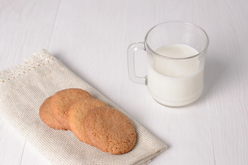 Homemade ginger cookies with a glass of milk on a wooden light b