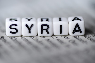 Word SYRIA formed by wood alphabet blocks on newspaper