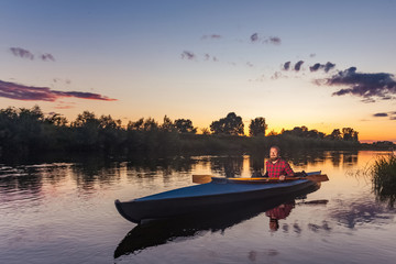 Fototapeta na wymiar sporty man kayaking on river surrounded by forest at sunset