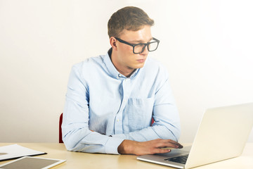 Portrait of young man sitting at his desk in the office using laptop