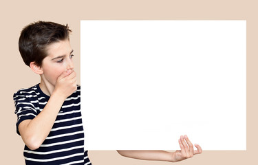 Surprised young boy with hand over his mouth holding and looking at the blank white board