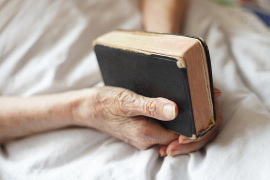 Hands of a senior woman on cane. Senior lying in a bed.