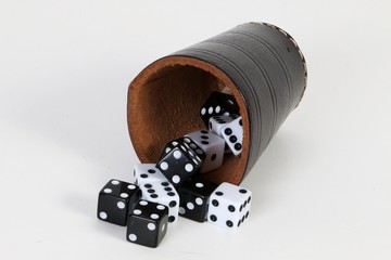 black and white dices are lying in the studio with a cup