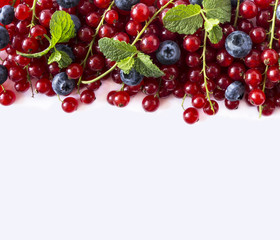 Blue and red food on a white. Ripe blueberries and red currants on a white background. Mixed berries at border of image with copy space for text. Top view.