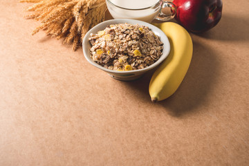 Oatmeal flakes in a bowl, milk, apple and banana on wooden table. Healthy breakfast concept. copy space
