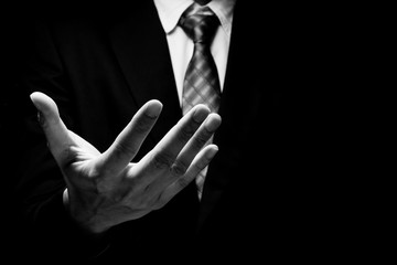 Close up of man in black suit with hand gesture on black background. black and white tone