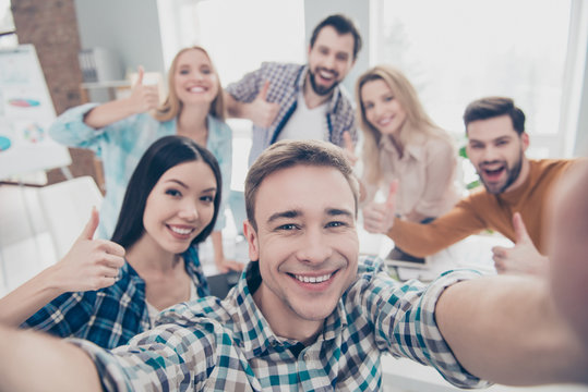 Self portrait of cheerful positive stylish confident economists shooting selfie on front camera showing thumb up, like sign with fingers having relax rest pause break timeout in work place