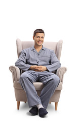 Young man in pajamas sitting in an armchair and looking at the camera