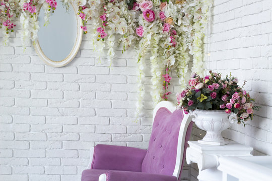 Wall decorated with flowers and mirror in loft interior room with vintage style sofa