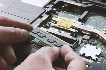Installing memory modules in the laptop with human hands in natural light close-up