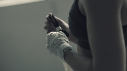 Boxer woman wrapping her wrists with protective bandage - Powered by Adobe