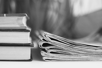 Pile of books and stack of newspapers, side view, selective focus